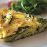 Slice of frittata on a plate with greens